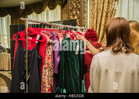 Groupe de jeunes belles femmes shopping in Fashion Mall, de choisir de nouveaux vêtements, regardant à travers des cintres avec différentes robes Banque D'Images