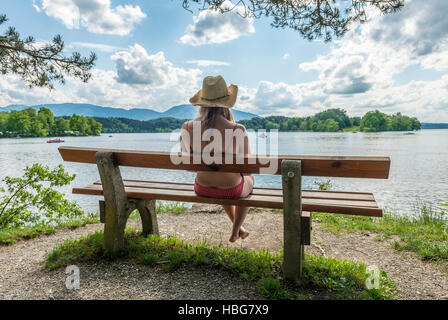 Femme assis sur un banc en bikini, le lac Staffelsee, Murnau, Upper Bavaria, Bavaria, Germany Banque D'Images