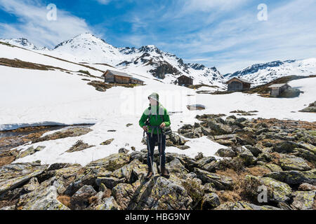 Jeune homme, randonneur debout devant des cabanes, Gweerhofstrasse Giglachsee, paysage de montagne avec de la neige résiduelle, Rohrmoos Obertal Banque D'Images