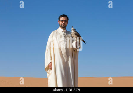 Homme tenant un faucon sacre oh son bras contre un ciel bleu Banque D'Images