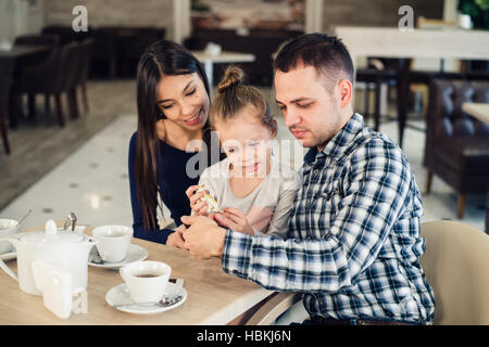 La famille, la parentalité, la technologie les gens heureux concept - mère, père et petite fille ayant pris le dîner au restaurant du smartphone par selfies Banque D'Images