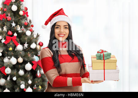 Jeune femme avec présente devant un arbre de Noël isolé sur fond blanc Banque D'Images