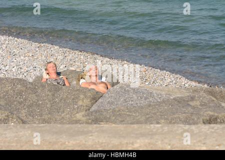 Couple de soleil sur les rochers sur septembre chaud jour dans Sheringham, Norfolk, Angleterre Banque D'Images