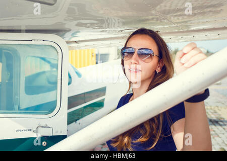 Young smiling woman standing près de l''avion prêt pour le vol. Banque D'Images