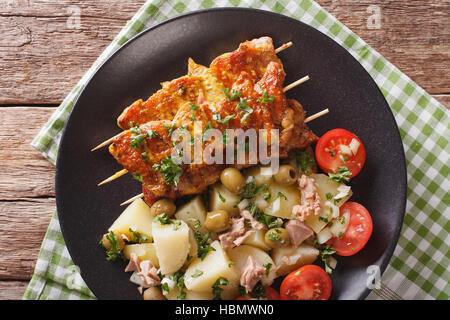 La cuisine espagnole : kebab Pinchos Morunos et salade de légumes sur une assiette sur la table horizontale vue du dessus. Banque D'Images