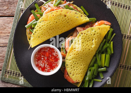 Le vietnamien Banh Xeo crèpes farcies avec le porc, les crevettes et les fèves germées et une sauce sauce nuoc cham libre sur une plaque horizontale vue du dessus. Banque D'Images