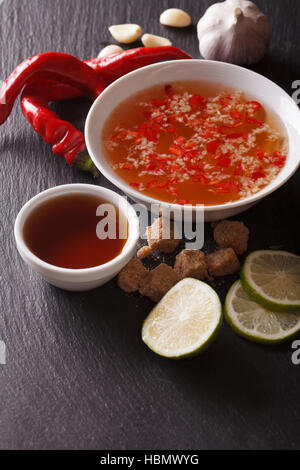 Sauce nuoc cham épicé vietnamien avec les ingrédients dans un bol close-up vertical. Banque D'Images