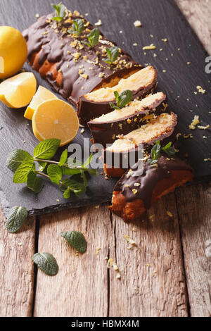 Tranches de citron gâteau avec lustre de chocolat et le zeste de close-up sur la table verticale. Banque D'Images