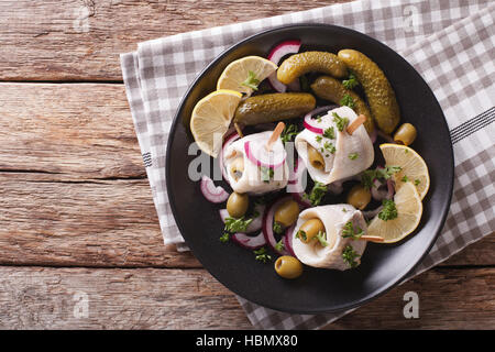 Rouleaux de hareng mariné aux olives, d'oignons, de cornichons et de citron sur une assiette sur la table. Vue du dessus horizontale Banque D'Images