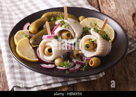 Rollmops savoureuses olives farcies, oignons, cornichons et de citron sur une assiette sur la table. L'horizontale Banque D'Images