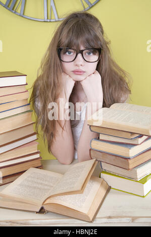 Girl à lunettes assis derrière les livres. Banque D'Images