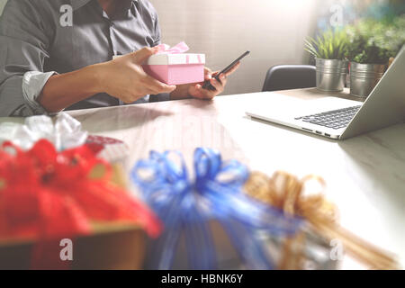 Donner de cadeau main créatrice le choix et la main avec don. Livraison de cadeaux, surprise, ordinateur portable et téléphone intelligent sur mable 24,effet film filtre Banque D'Images