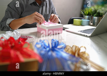 Donner de cadeau main créatrice le choix et la main avec don. Livraison de cadeaux, surprise, ordinateur portable et téléphone intelligent sur mable 24,effet film filtre Banque D'Images