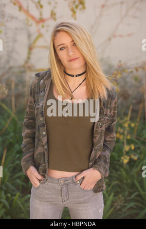 Adolescente blonde en jeans et haut vert, à l'extérieur. Banque D'Images