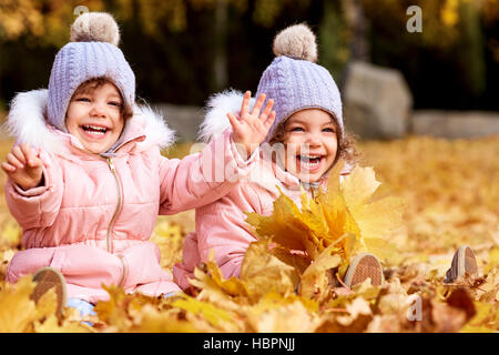 Deux sœurs jumelles dans un parc l'automne avec des feuilles jaunes de rire et de ha Banque D'Images