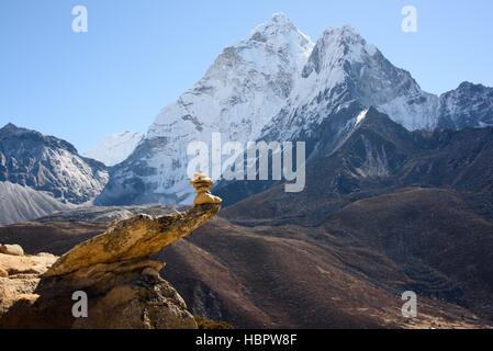 Cairn en équilibre sur un rocher saillant en face d'un pic himalyan Banque D'Images