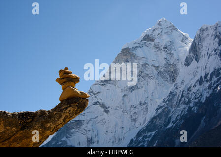 Cairn en équilibre sur un rocher saillant en face d'un pic himalyan Banque D'Images