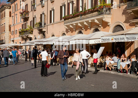 Piazza Navona, Rome, les touristes à manger al fresco restaurant au soleil, avec serveurs et couple walking par Banque D'Images