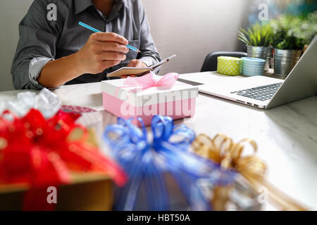 Donner de cadeau main créatrice le choix et la main avec don. Livraison de cadeaux, surprise, ordinateur portable et téléphone intelligent sur mable 24,effet film filtre Banque D'Images