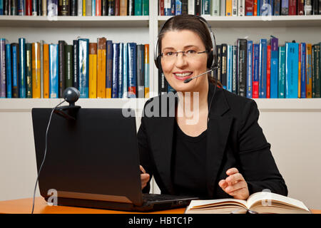 Femme avec casque, ordinateur et webcam dans son bureau, consultant, conseiller, enseignant, l'apprentissage en ligne, l'entreprise Banque D'Images