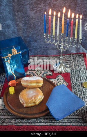 Hanukkah Menorah avec allumé des bougies, des cadeaux, et rempli de gelée Dreidels pâtisseries servi sur une plaque de bois pour la Maison de Vacances Banque D'Images