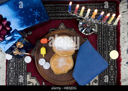 Hanukkah Menorah avec allumé des bougies, des cadeaux, et rempli de gelée Dreidels pâtisseries servi sur une plaque de bois pour la Maison de Vacances Banque D'Images