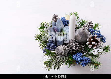 Noël arrière-plan avec la bougie et poinsettias en soie bleue. Arrangement de fleurs de Noël artificiel avec des pommes de pin et branches de sapin. Table de Noël Banque D'Images