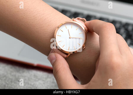 Girl's hand with wrist watch en face de bureau avec ordinateur portable Banque D'Images