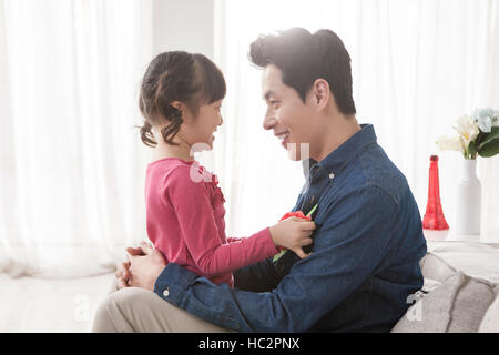 Vue latérale du père aimant et sa fille avec fleur oeillet hugging face à face Banque D'Images