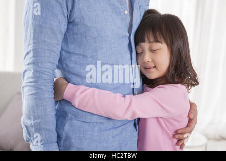 Six ans smiling Korean girl hugging son père avec ses yeux fermés Banque D'Images