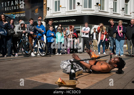 Un jongleur tente de passer sous le feu dans la place d'Arthur, Belfast, Irlande du Nord, Royaume-Uni. Arthur Square, également connu sous le nom de Cornmarket (il était auparavant de k Banque D'Images