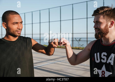 Portrait of a smiling deux joueurs de basket-ball fist bumping tout en se tenant à l'aire de jeux Banque D'Images