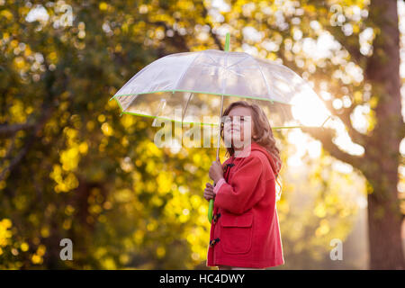 Vue latérale du girl holding umbrella contre des arbres Banque D'Images