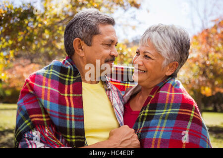 Vieux couple sitting on bench in avec une couverture Banque D'Images