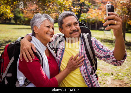 Un couple de personnes âgées marcher en tenant un selfies Banque D'Images