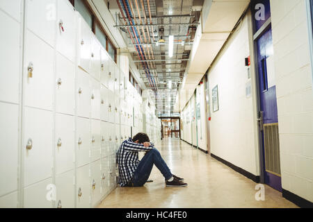 Déprimé student sitting in locker room Banque D'Images