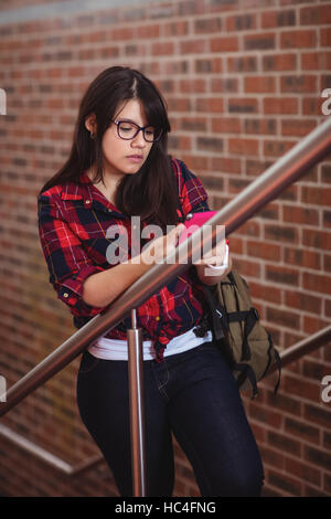 Étudiante marche sur escalier lors de l'utilisation de téléphone mobile Banque D'Images