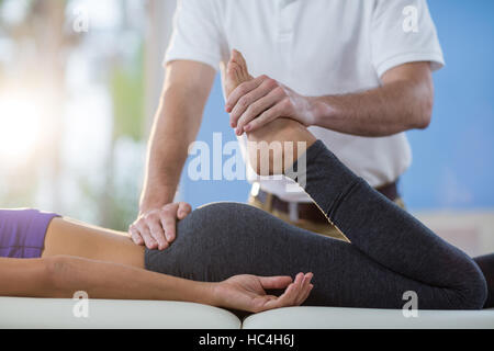 Physiothérapeute mâle à femelle massage du genou donnant patient Banque D'Images