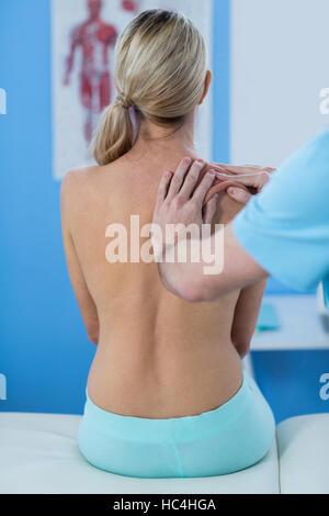 Physiothérapeute mâle à femelle massage épaule donnant patient Banque D'Images