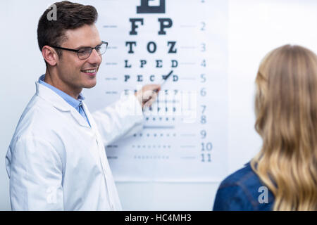 Optométriste prenant l'essai d'oeil du patient de sexe féminin Banque D'Images