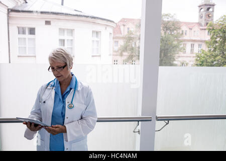 Doctor using digital tablet in corridor Banque D'Images