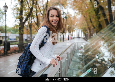 Smiling attractive young woman with backpack standing in park Banque D'Images