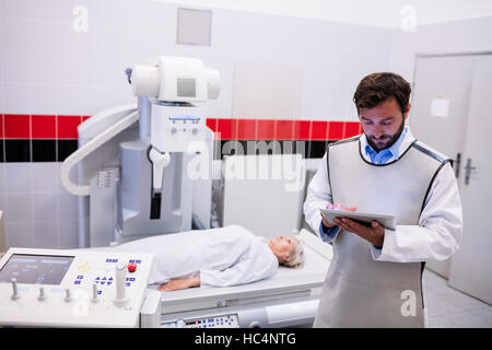 Doctor using digital tablet et patient couché sur la machine à rayons x Banque D'Images