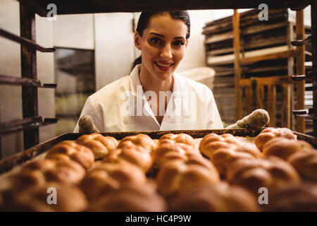 Portrait of female baker holding a tray de michetta Banque D'Images