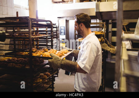 Male baker holding a tray de michetta Banque D'Images