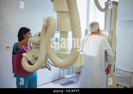 Femme médecin met en place la machine à rayons x de la colonne vertébrale d'un patient Banque D'Images