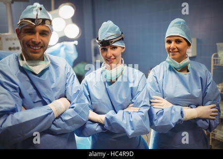 Portrait de chirurgien et les infirmières debout avec les bras croisés en salle d'opération Banque D'Images