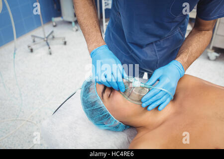 Chirurgien mâle mettre un masque à oxygène sur patient Banque D'Images