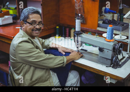 Portrait of smiling shoemaker à l'aide de la machine à coudre Banque D'Images