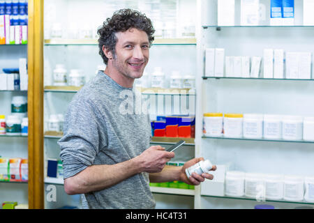 Client à l'aide de téléphone mobile avec une bouteille de médicament dans la main Banque D'Images